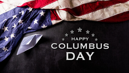 Fototapeta na wymiar Happy Columbus Day concept. Vintage American flag with paper boat with the text on dark stone background.