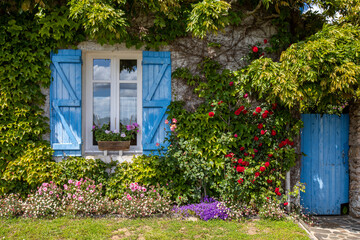 Petit jardin et façade d'une vieille maison charmante et fleurie.