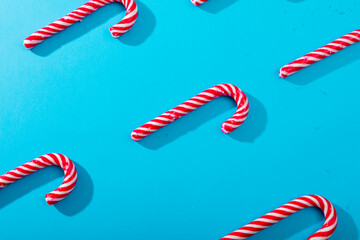 Composition of multiple rows of candy canes on blue background
