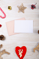 Composition of white card with copy space, envelope and christmas decorations on wooden background