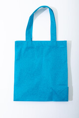 Composition of empty blue canvas shopping bag lying flat on white background