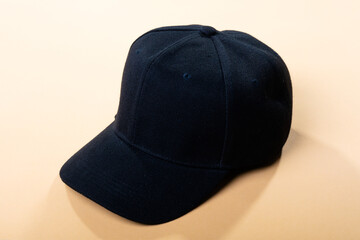 Composition of traditional peaked black baseball cap on pale brown background