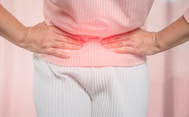 Young sick woman with hands holding her belly suffering menstrual period pain at home. Gynecology...