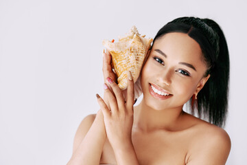 Smiling african american woman pressed conch seashell to her ear enjoy and dreams