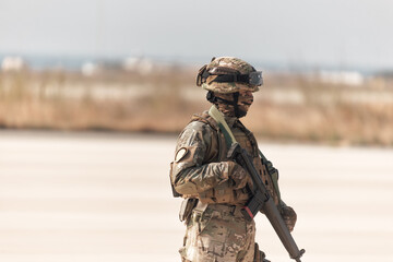 Modern soldier in full protective equipment holding assault rifle