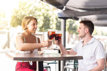 Young couple toasting on a bar terrace looking into each other's eyes and smiling