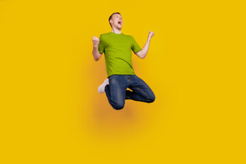 Full length photo of guy having fun jump up excited crazy celebrate victory isolated over yellow...