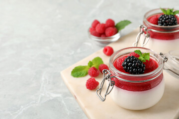 Delicious panna cotta with fruit coulis and fresh berries on light grey table. Space for text