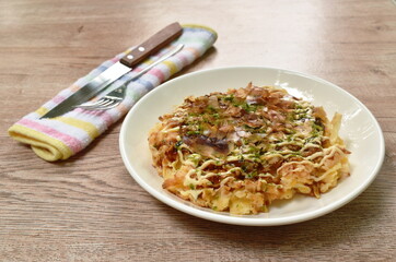 Okonomiyaki or Japanese pizza grilled on pan topping slice bacon and seaweed  dressing mayonnaise on plate
