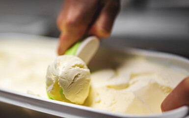 Woman hand scooping ice cream from tray in scoop