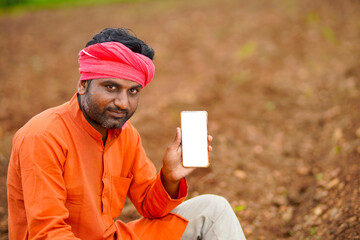 technology concept : Young indian farmer showing smartphone.