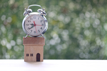 Estate tax,Alarm clock on model house on green background,Business investment and Property tax concept