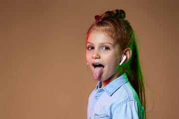 happy redhead child girl in earphones listening to music on beige background