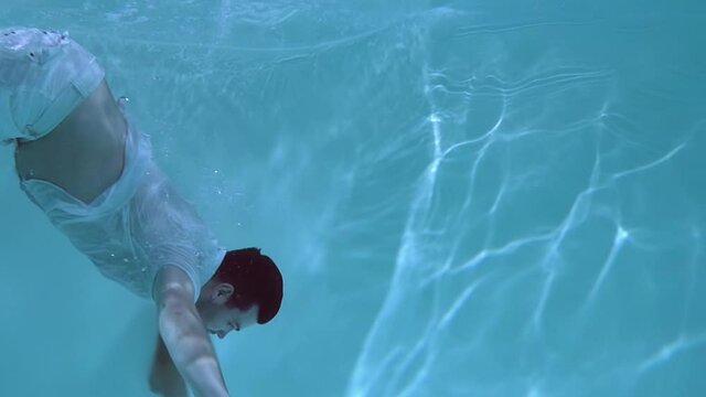 Man in clothes wallows underwater. He sinks into the water.