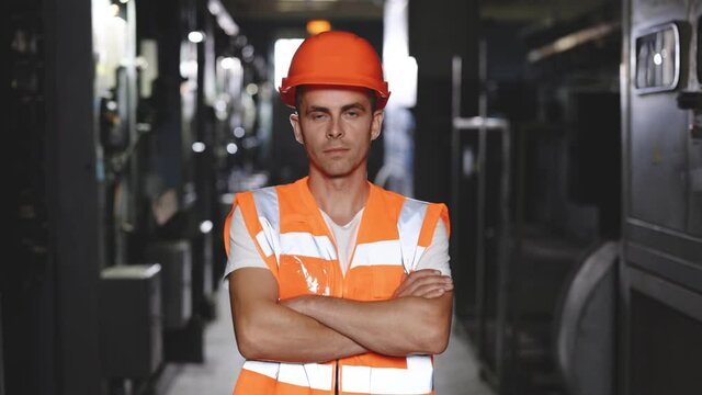Portrait of an engineer man or worker crossing arms, working in electrical room station. Power energy motor machinery cabinets in control or server room, operator station network in industry factory