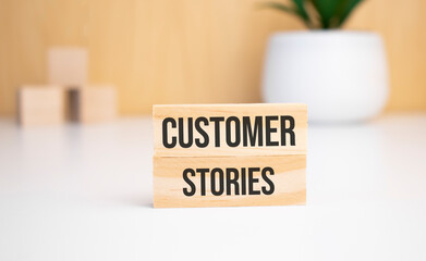 On a light background, wooden cubes and a wooden block with the text customer stories. View from above