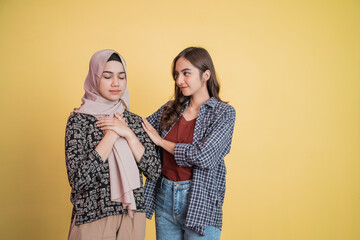 a muslim woman with a panicked gesture and a friend calming her down