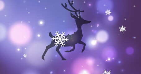 Obraz na płótnie Canvas Image of black silhouette of two reindeer running with snow falling and spots of light on purple