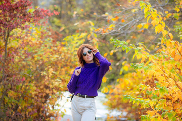 a young woman in an autumn park in a purple sweater
