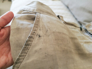 Dirty shorts in hand. Oil stain or grease stain on clothes. 