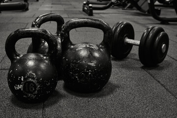Naklejka na ściany i meble Dumbbells and kettlebells on a floor. Bodybuilding equipment. Fitness or bodybuilding concept background. black and white photography