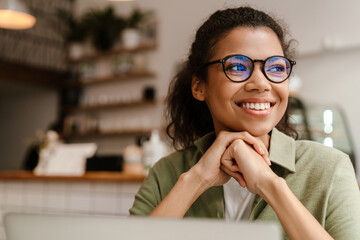 Young black woman working with laptop while sitting at cafe