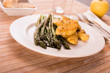cooked dish. Chicken nuggets with green asparagus on plate