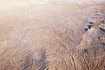 Tire tracks and footprints all over the sandy beach.