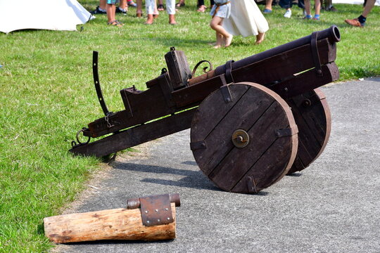A close up on a wooden cannot or bombard on wheels with some metal elements and barrel standing on an asphalt field prepared for shooting seen during a medieval fair in Poland on a sunny summer day