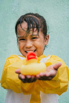 Smiling Asian girl with toy duck in rainy weather