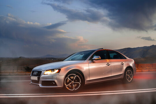 audi a4 car on the background of a sunset on a mountain road. illustrative editorial. added artificial noise/grain and smoke