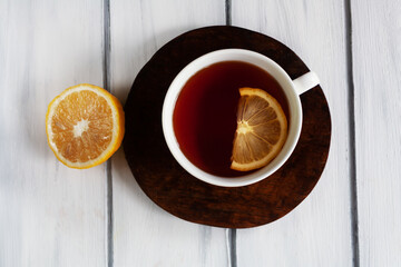 Horizontal image of a white cup of tea with lemon.