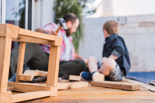 Unrecognizable dad with son working with wood on weekend