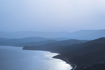 Obraz premium Layered silhouettes of mountains in a blue haze at dawn or sunset. Beautiful natural landscape