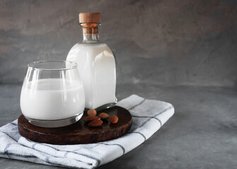 .Bottle and glass cup with almond milk on gray background