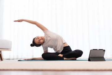 Productive activity concept a female young adult wearing a white t-shirt practicing the flexibility of her body by doing mat pilates