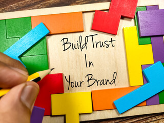 Business concept.Text Build Trust In Your Brand writing on wooden puzzle board on a wooden background.