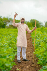 Young indian farmer standing in cotton agriculture field.