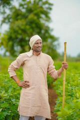 Young indian farmer standing in cotton agriculture field.