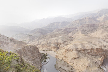 Layers of rocky mountains and hills in the morning haze, bend of a river in a canyon, sepia,...