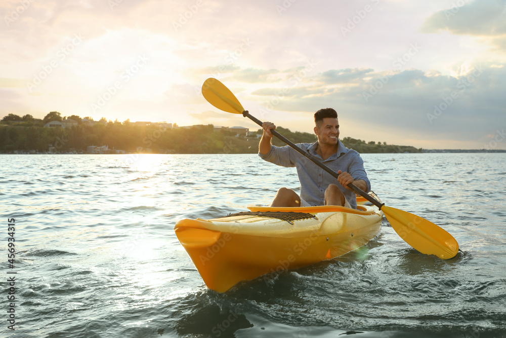 Sticker Happy man kayaking on river at sunset. Summer activity