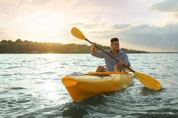 Happy man kayaking on river at sunset. Summer activity