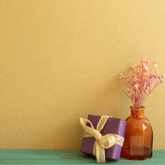 Purple gift box and dry flowers on wooden table. khaki brown wall background. copy space