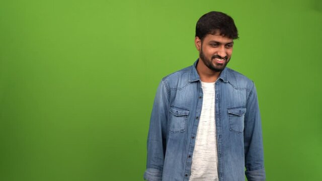 Male inhabitant of Asia in blue denim jacket and white tee nodding his head in disapproval on green screen