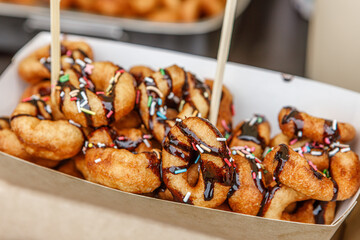 Fresh, crunchy, delicious donuts, sprinkled with sugar and poured with syrup in a paper plate.
