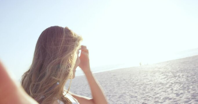 beautiful woman taking selfie using phone on beach at sunset smiling and spinning on vacation
