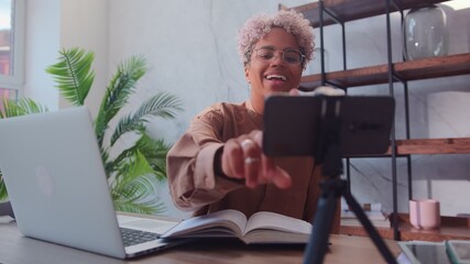 Happy african american woman turns on cell phone camera to record video. Beautiful young woman...