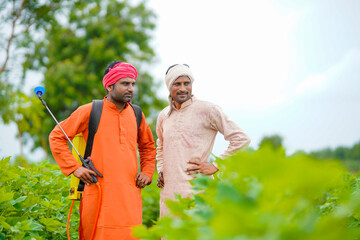 Two indian farmers working and discuss at green cotton field.