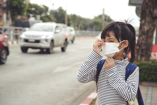 Cute asian child girl wearing protection mask to against air smog pollution with PM 2.5 in the city
