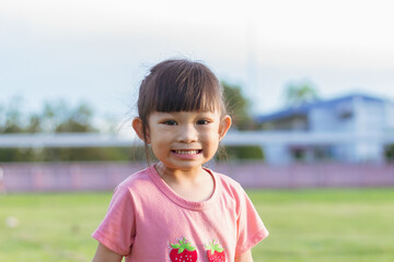 Portrait​ image of​ 3-4 years old​ baby​ child. Face of smiling​ Asian​ girl in head shot. Happy​ kid playing​ at the park playground. In summer or spring​ season.
